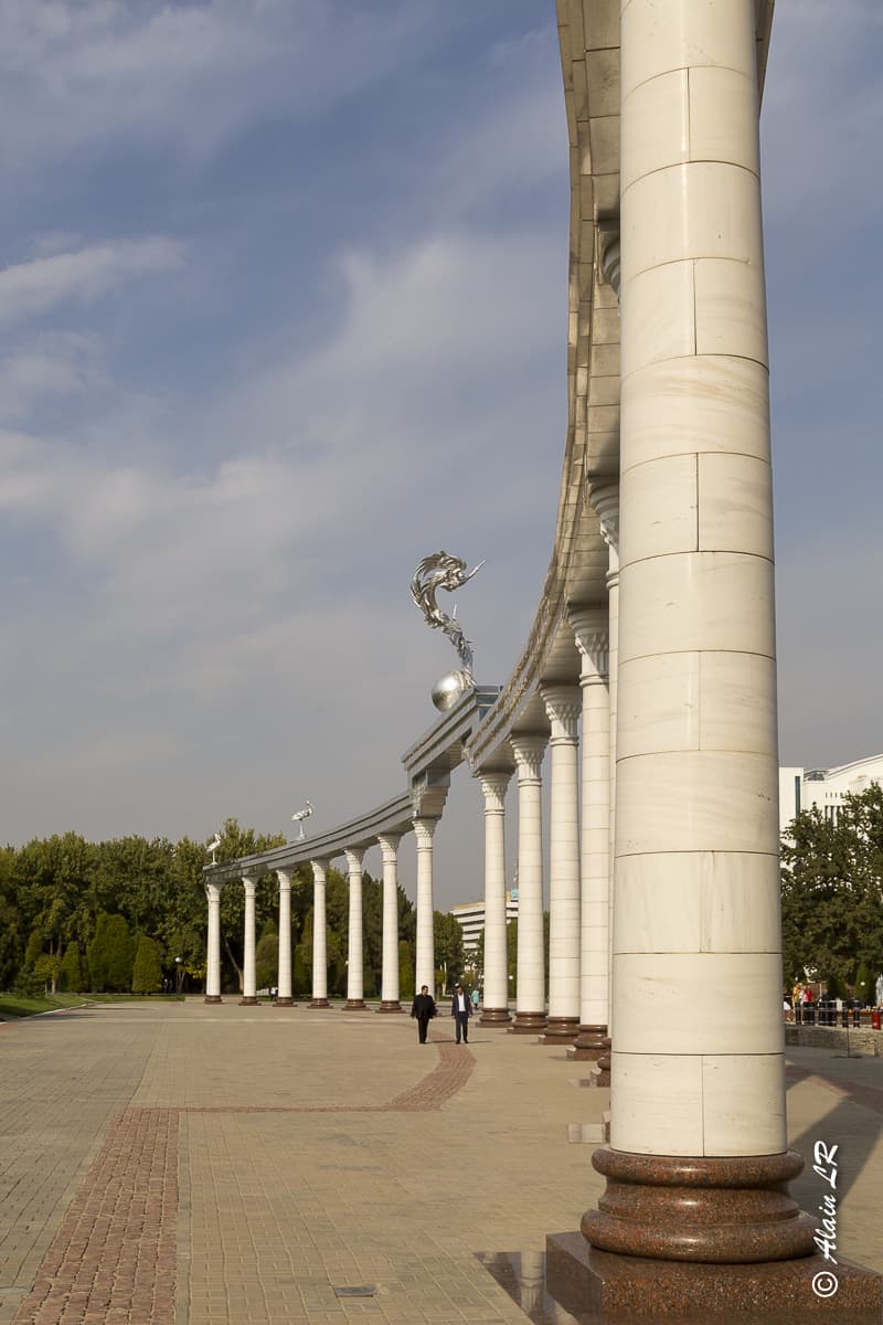 Place Mustakillik (de l'indépendance). La série de colonnes est surplombée d'une arche argentée portant des oiseaux légendaires : les humos